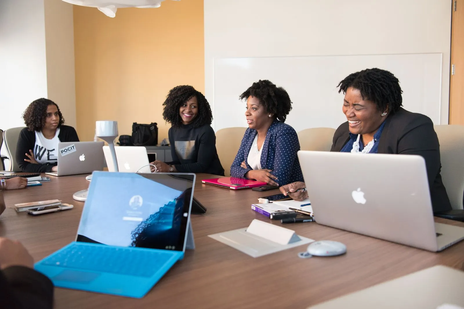 Colleagues working together on laptops around a table in a bright office