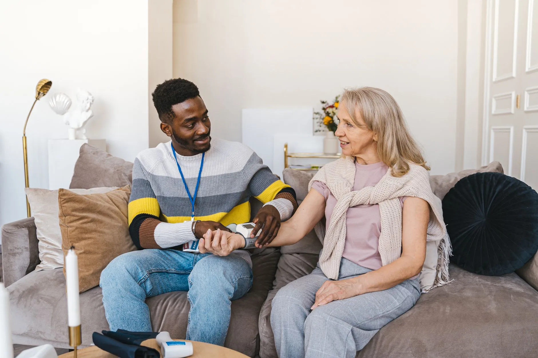 A care worker checking an older woman's blood pressure in her living room