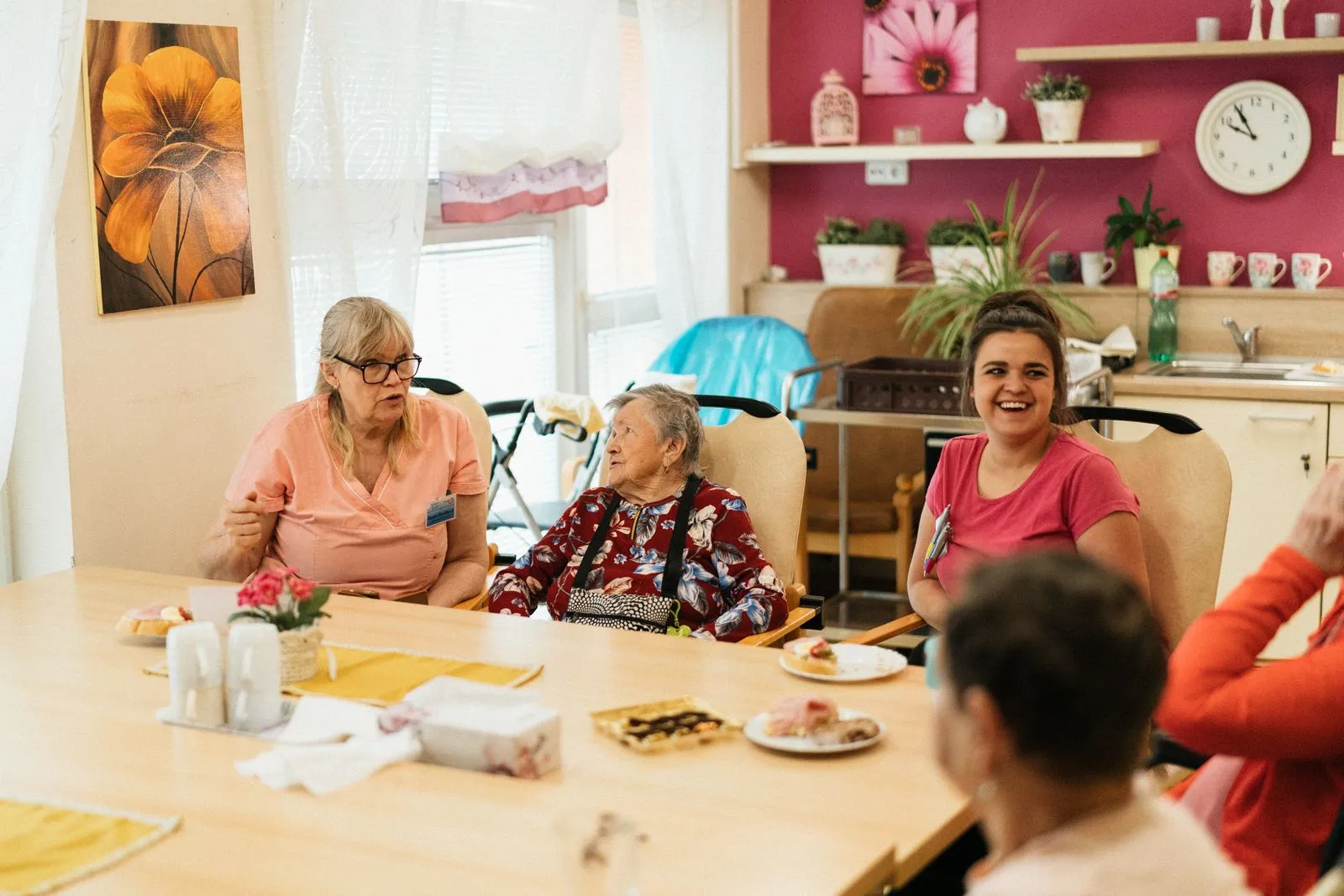 Care team members talking with a resident over coffee in a community dining room