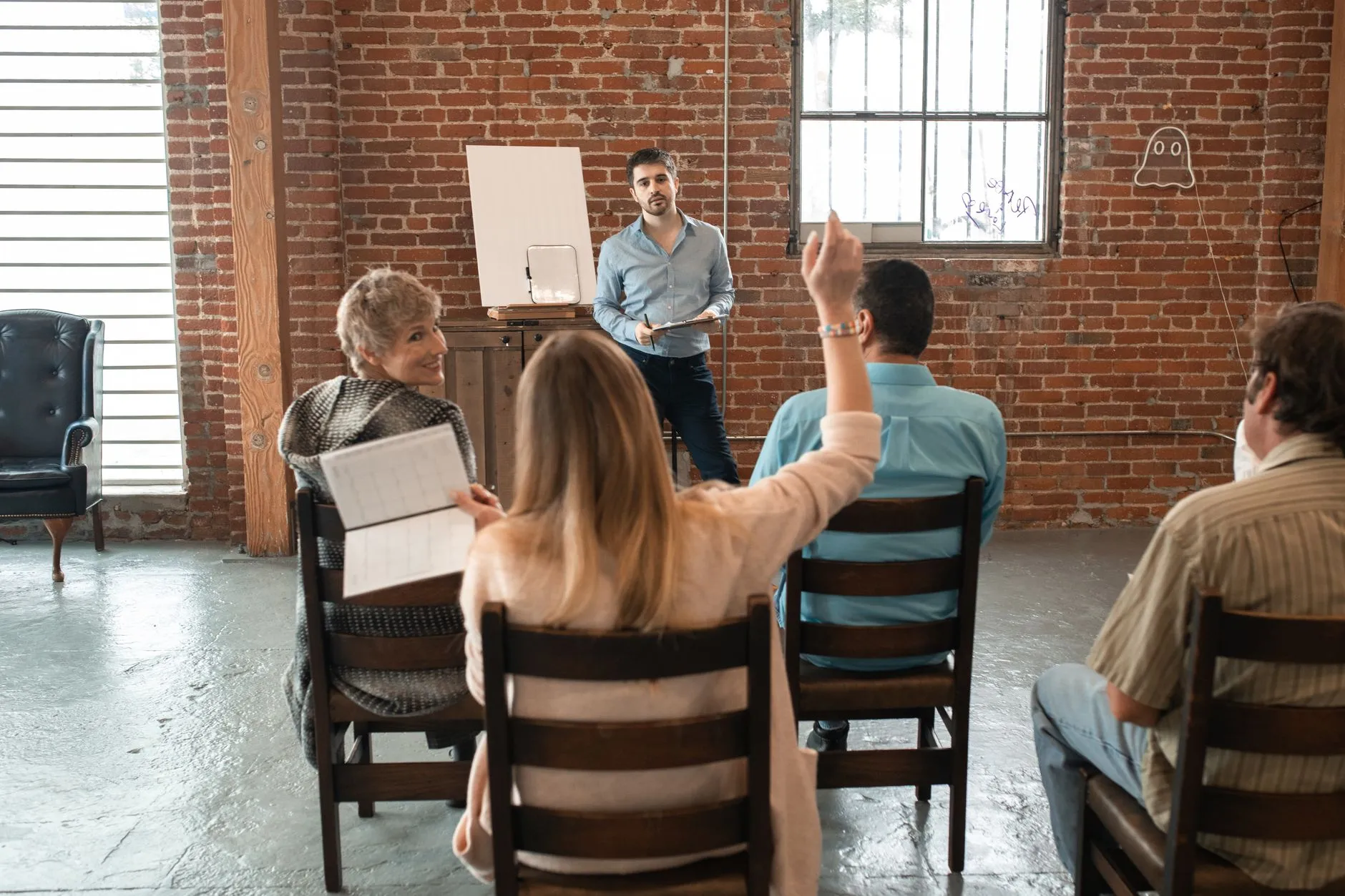 Care team members in an in-service session, one raising a hand to ask a question