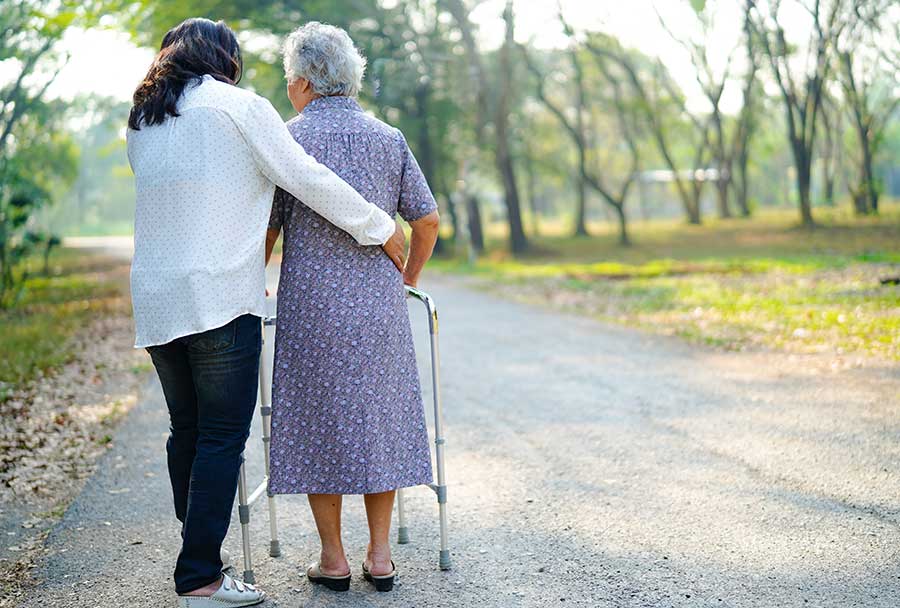 care options helping elderly woman walk with a walker